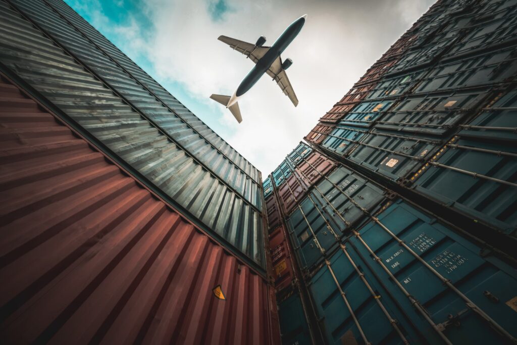 A plane flying over shipping containers